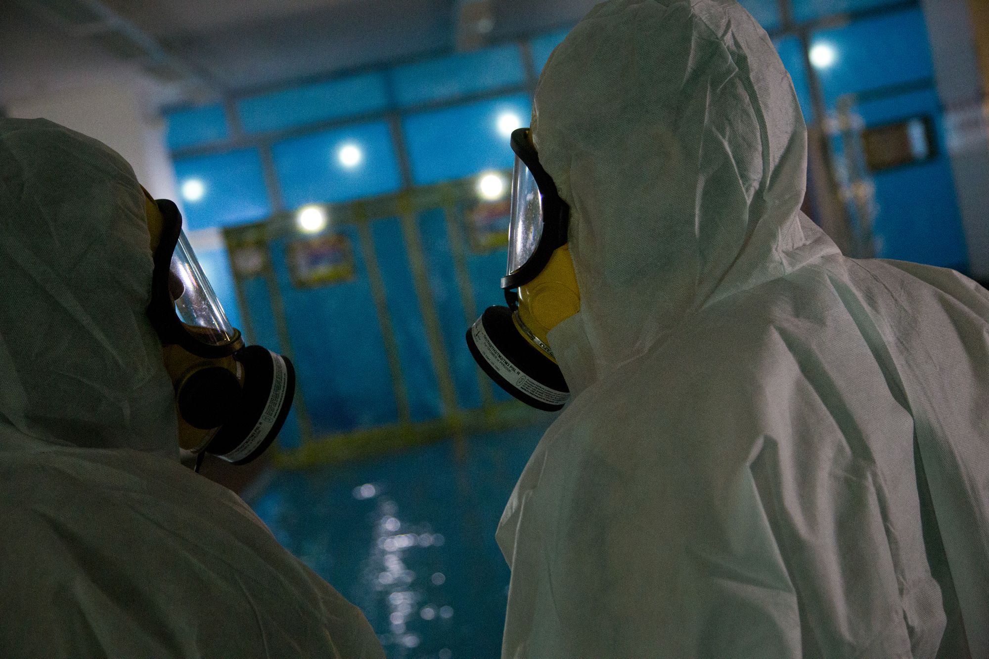 Two asbestos removal technicians in full PPE working inside a sealed enclosure